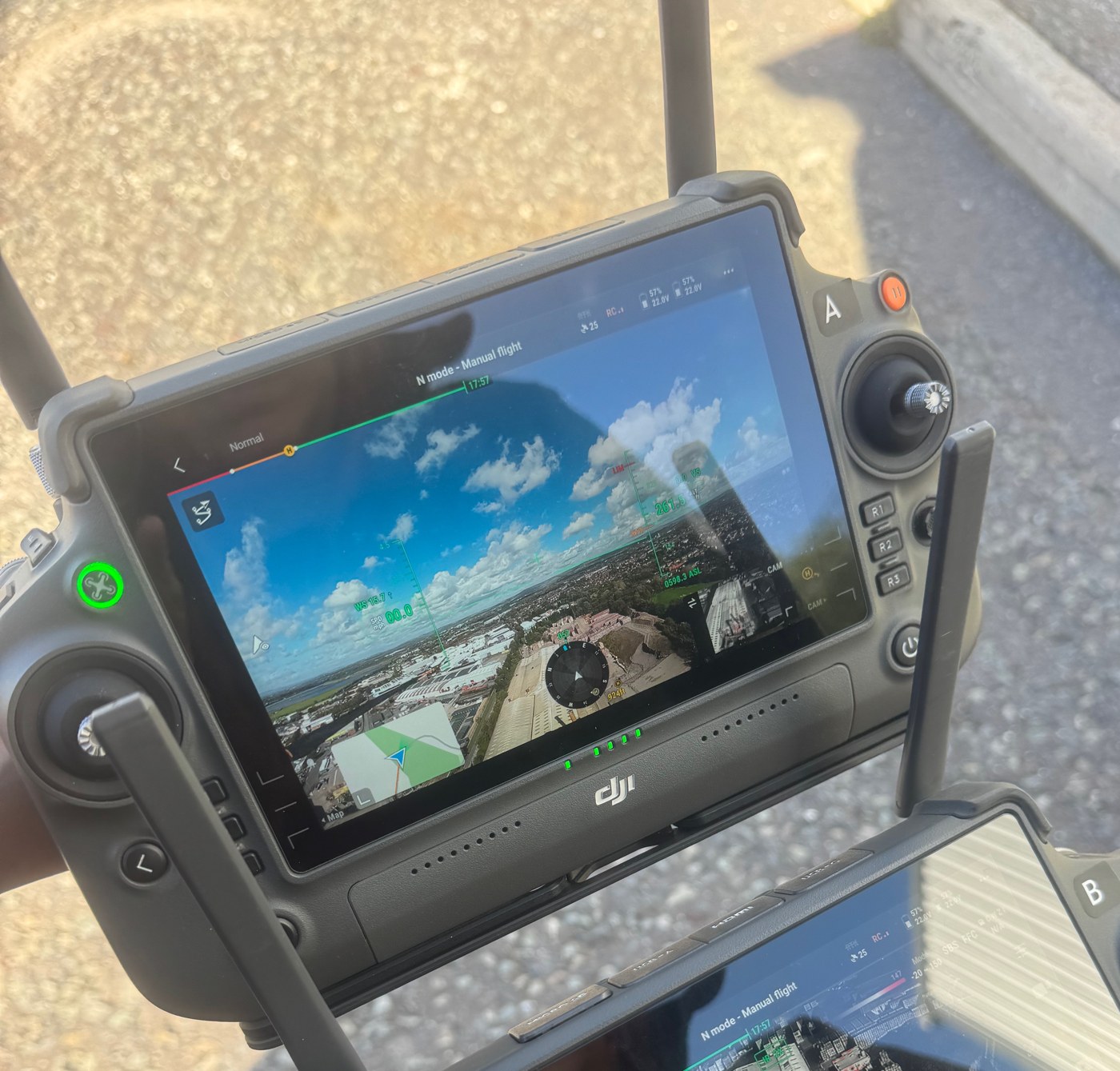 Drone controller displaying an aerial camera view of an industrial area