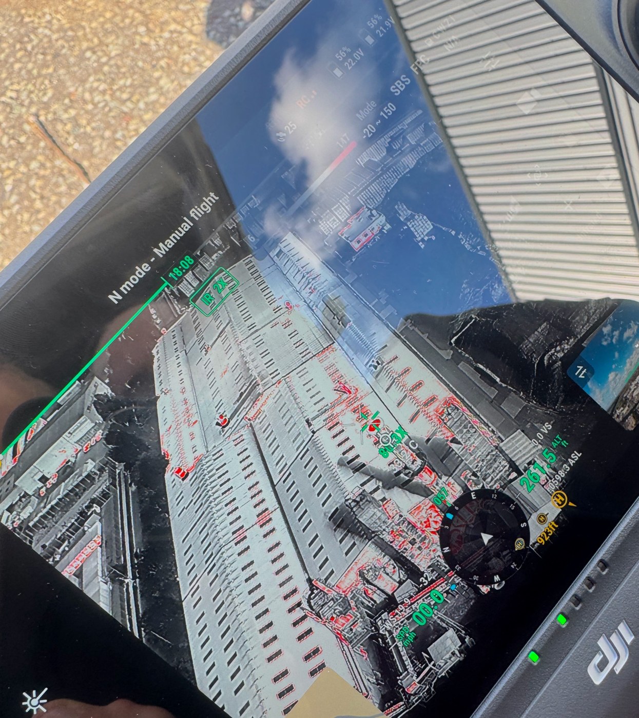 Drone controller showing a thermal camera view of buildings and vehicles